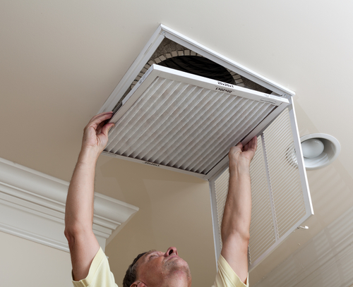 Man changing HVAC air filter in his South NJ home